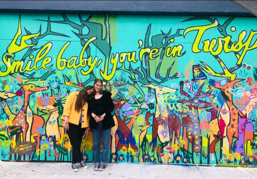 two people stand in front of mural